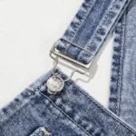 Piper Denim Straight Leg Jumpsuit with Pockets - A casual yet chic denim jumpsuit featuring a straight leg cut, practical pockets, and a timeless design, ideal for effortless everyday style. Displaying a closeup of straps hardware against all white background.
