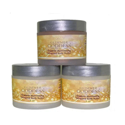 Organic shimmering whipped body butter trio in three jars, displayed on a wooden surface with natural ingredients like shea butter and coconut oil, perfect for deep hydration and glowing skin. Displayed in front of a white background.