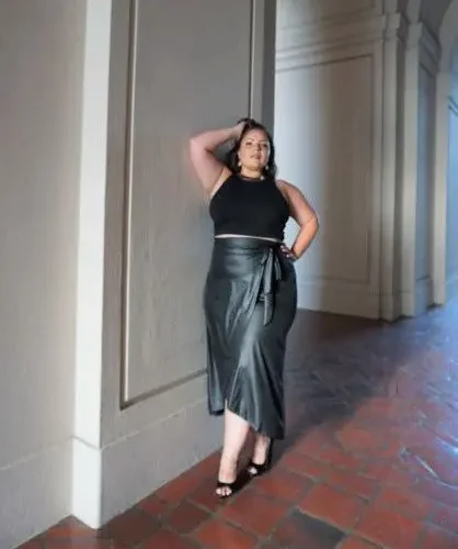 Model wearing a chic faux leather maxi wrap skirt with a high waist and side tie detail, showcasing a sleek, elegant look perfect for modern street style or evening wear.
