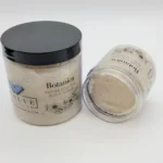 Botanica Sugar Soufflé Body Polish in a glass jar with natural sugar crystals and botanical oils – luxury exfoliating body scrub for glowing skin. Two jars displayed with one jar opened to show souffle texture.