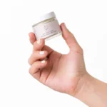 Extended hand holding lavender clay facial mask from spa gift box for calming skincare routine