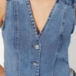Detailed view of cropped denim vest on model highlighting front buttons and tailored cropped silhouette